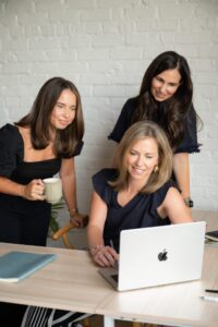 Three Ascent Strategic Communications team members grathered to view laptop computer.